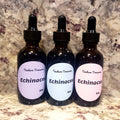Three amber glass dropper bottles labeled 'Tincture Treasures Echinacea' with lavender, light blue, and pale pink labels, set against a mottled stone countertop.