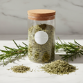 Rosemary herbal tea in a glass jar with fresh rosemary sprigs on white marble surface