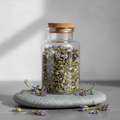 Skullcap herbal tea in a glass jar with purple skullcap flowers on a soft grey stone surface